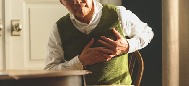 胸を両手でおさえる男性