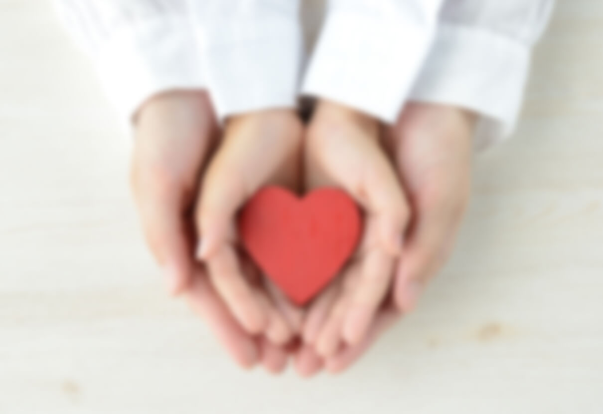 ハートの模型を両手で包み込む男女のイメージ